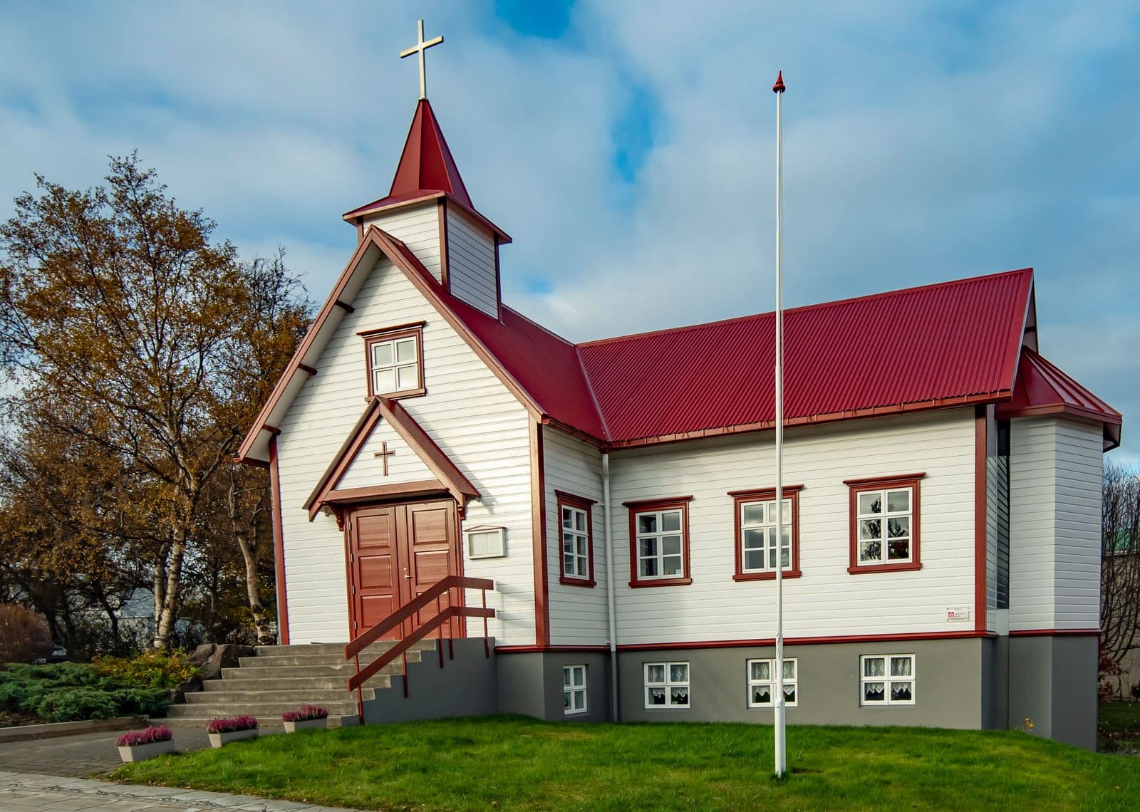 White church with a red roof and autumn trees in Akureyri