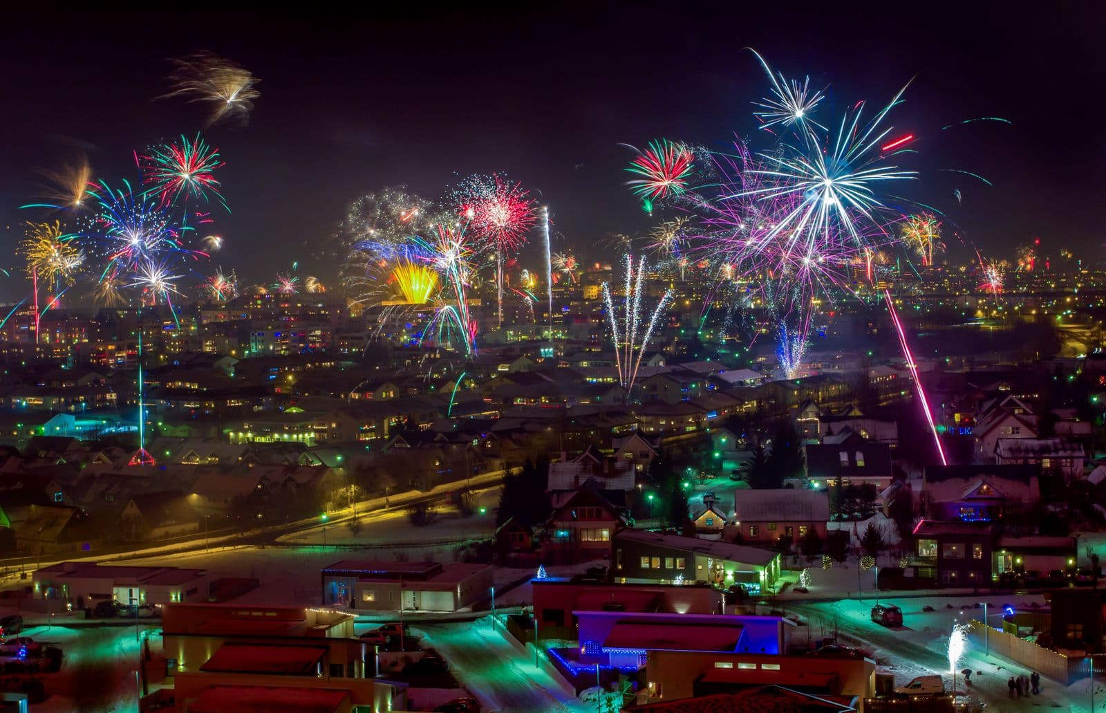 Colourful fireworks above a snow-covered Reykjavík neighbourhood at night