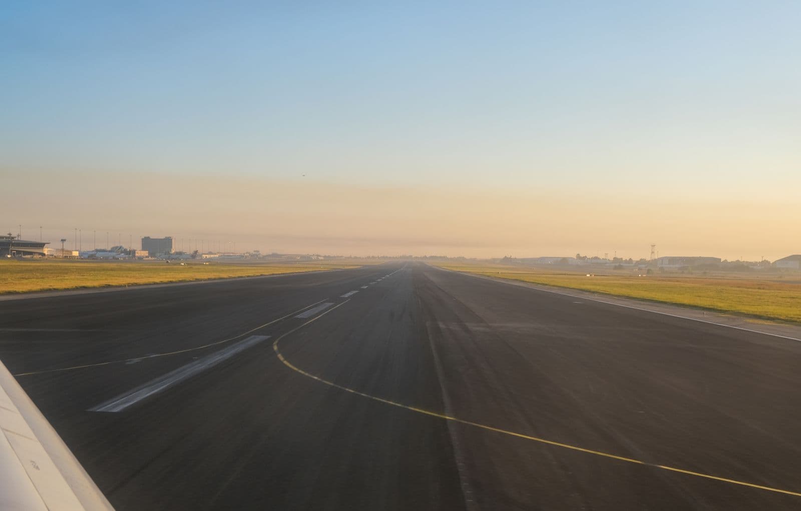 Empty airport runway at sunrise under a clear sky