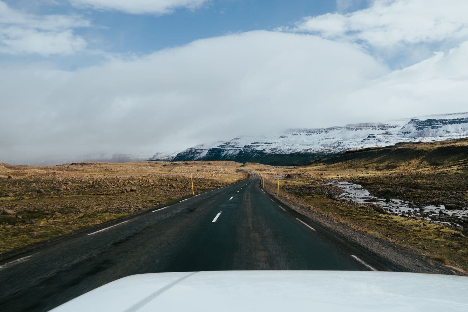 A road leading through the Icelandic landscape towards snow-capped mountains