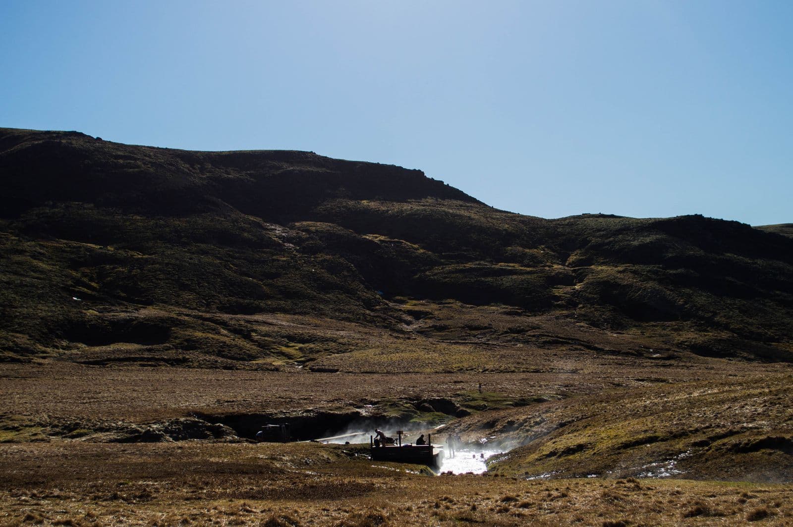 Steaming geothermal stream and a small wooden bathing platform in the Reykjadalur valley