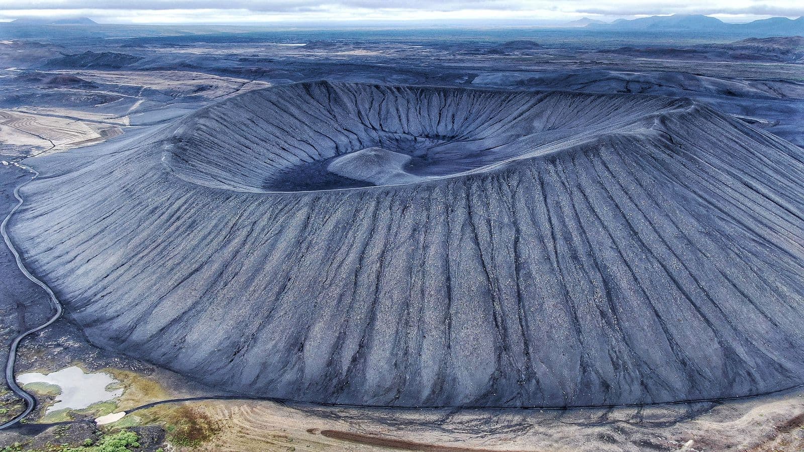 Aerial view of the large round Hverfjall crater with a path along its rim