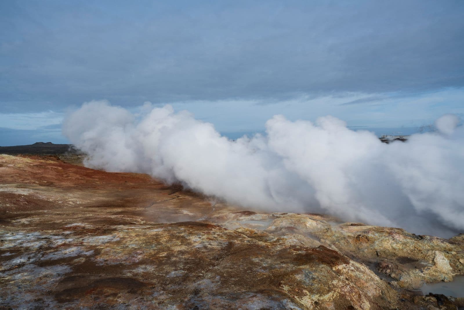 Clouds of steam rising from a geothermal area with orange and brown ground on the Reykjanes Peninsula