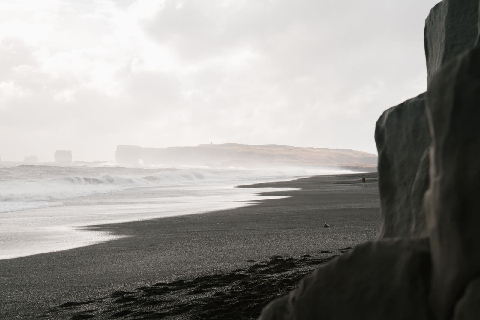Long black sand beach with surf and misty coastal cliffs on the South Coast of Iceland
