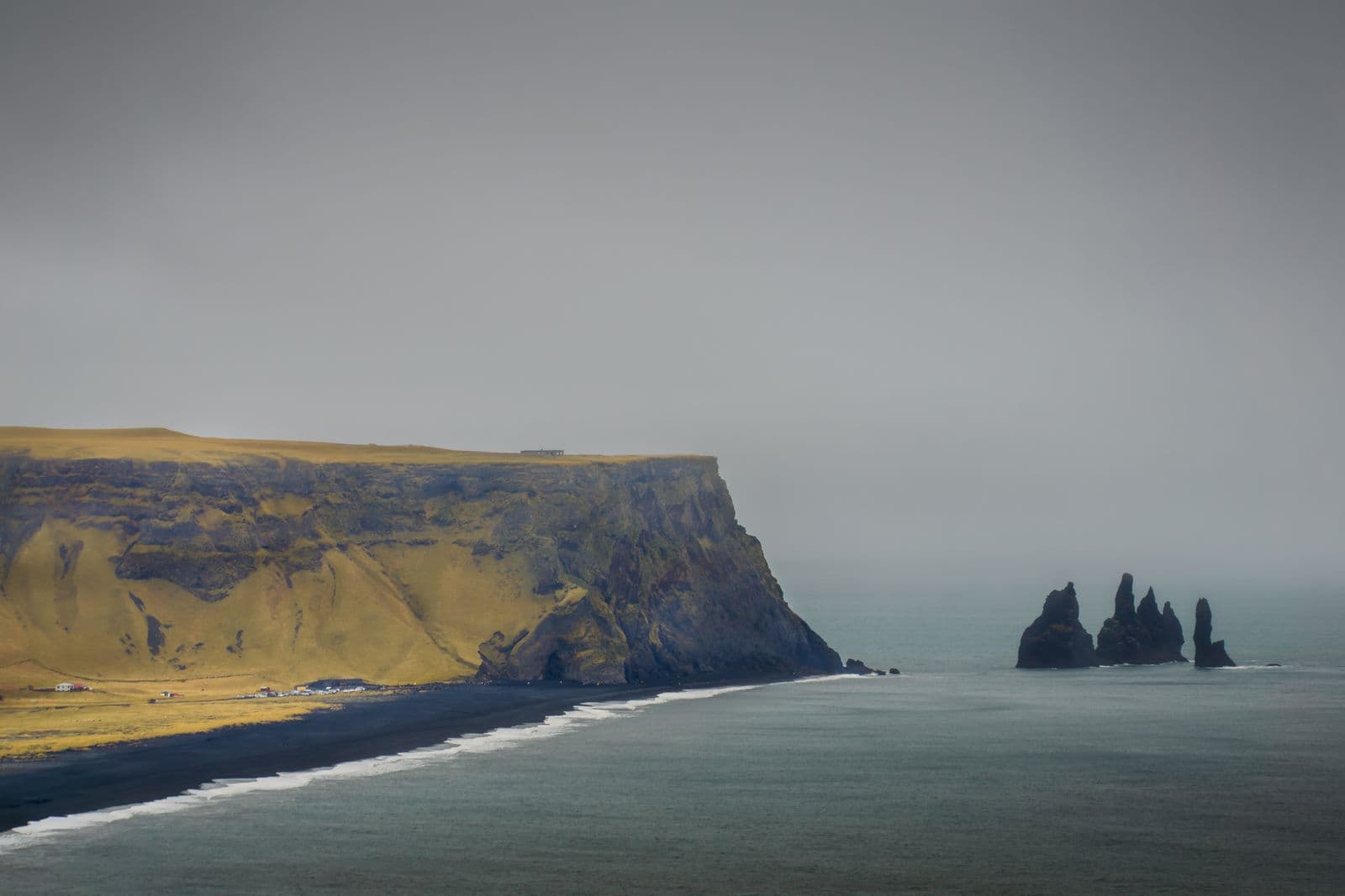 Black sand coast and the Reynisdrangar sea stacks seen from a high viewpoint on a grey day