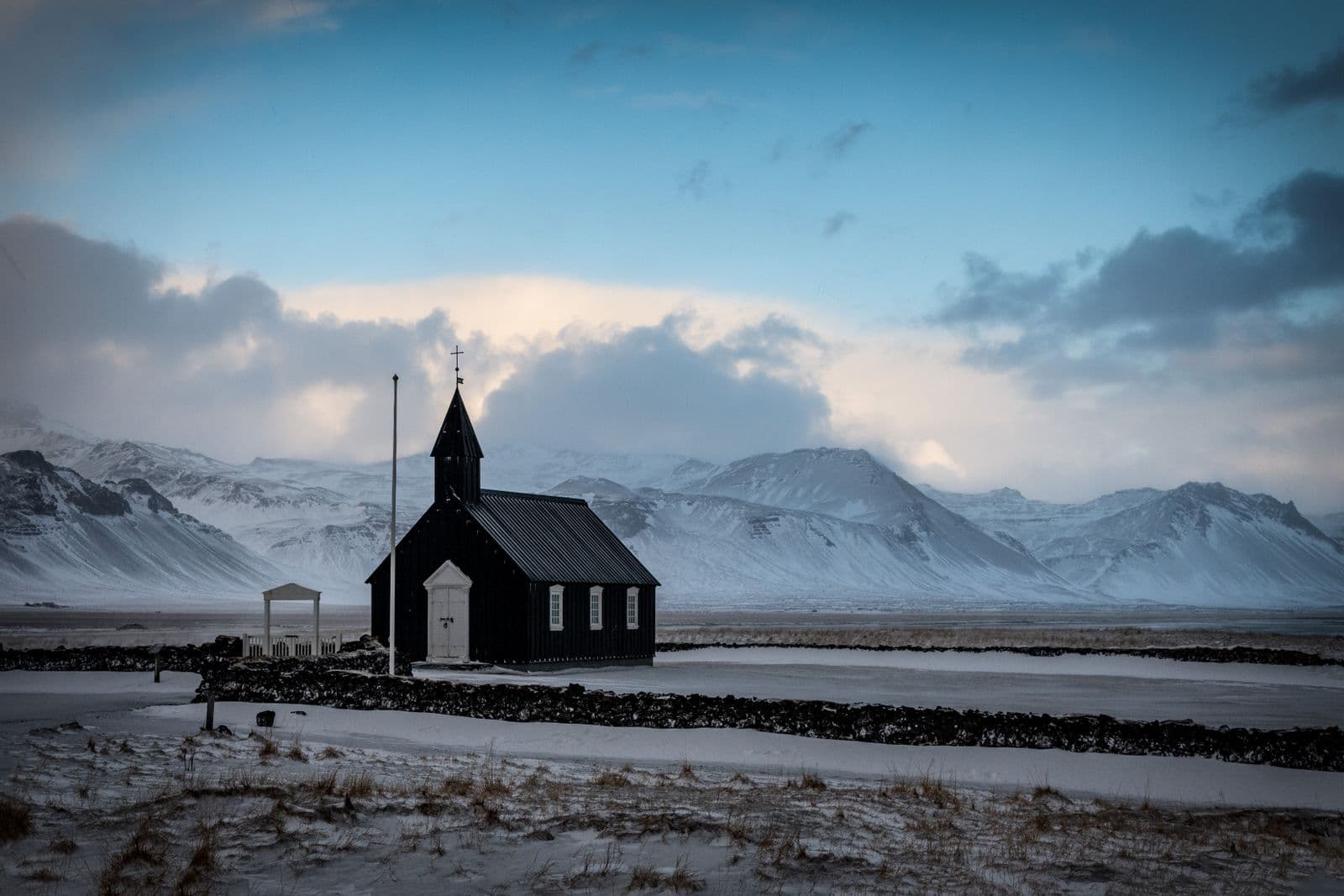 Black wooden church at Búðir with snowy mountains in the background