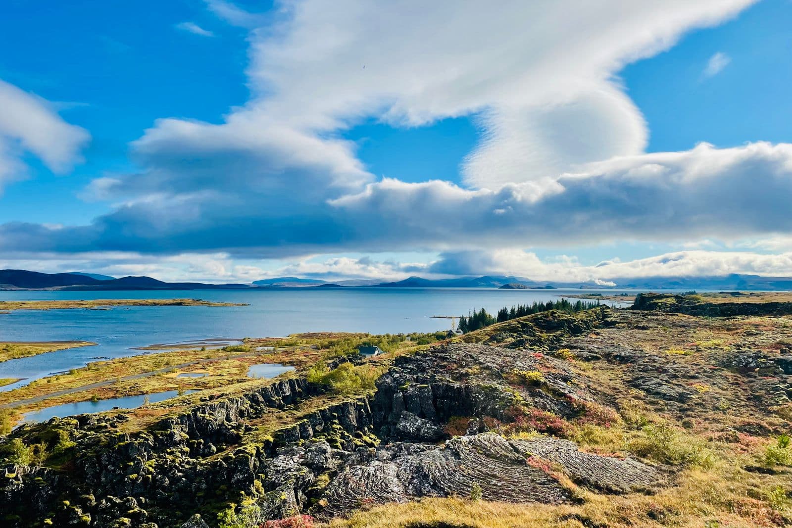 View across Lake Þingvallavatn and the lava landscape of Þingvellir under a blue sky