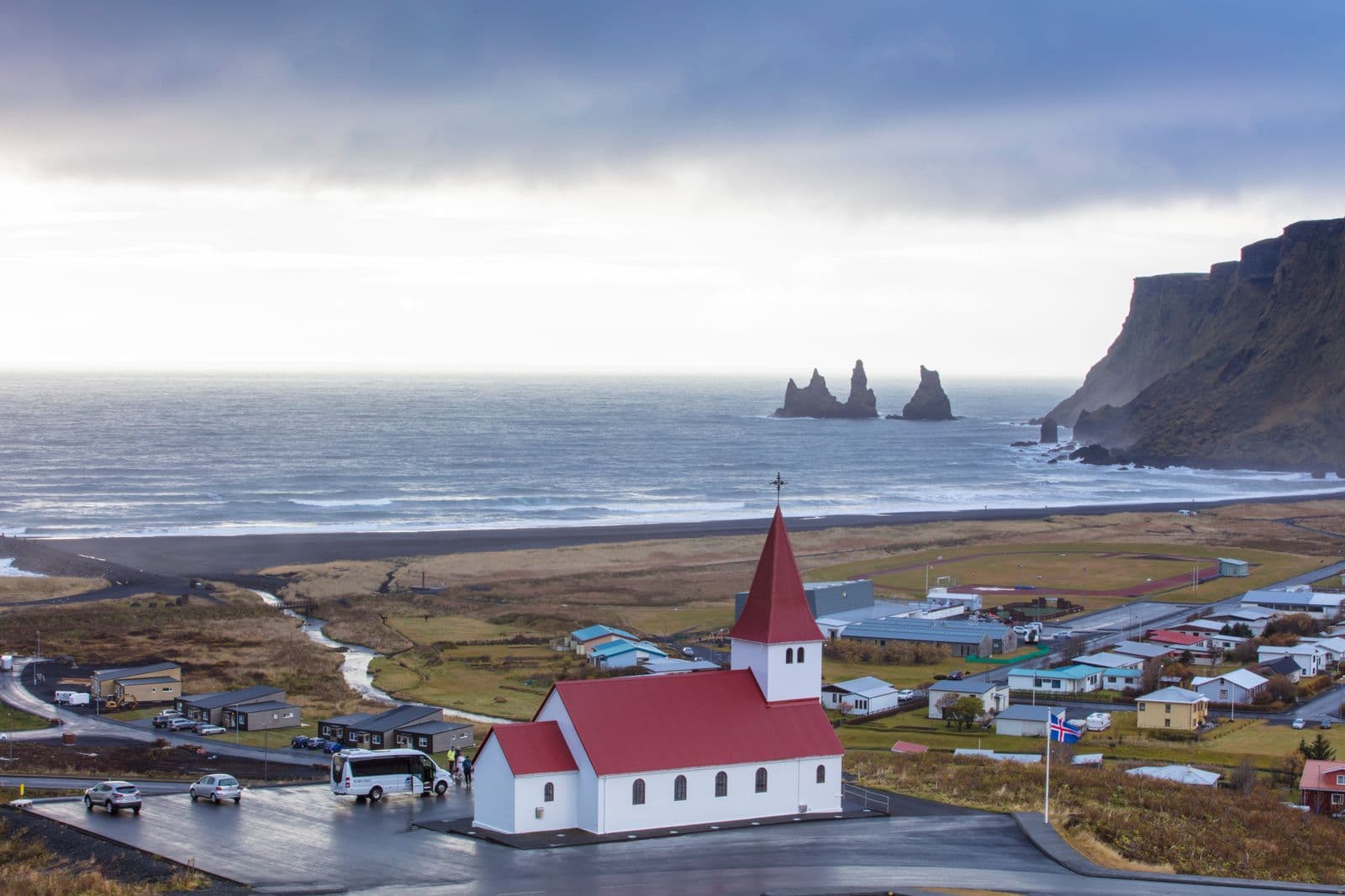 Red-roofed church above Vík with the sea and sea stacks in the distance