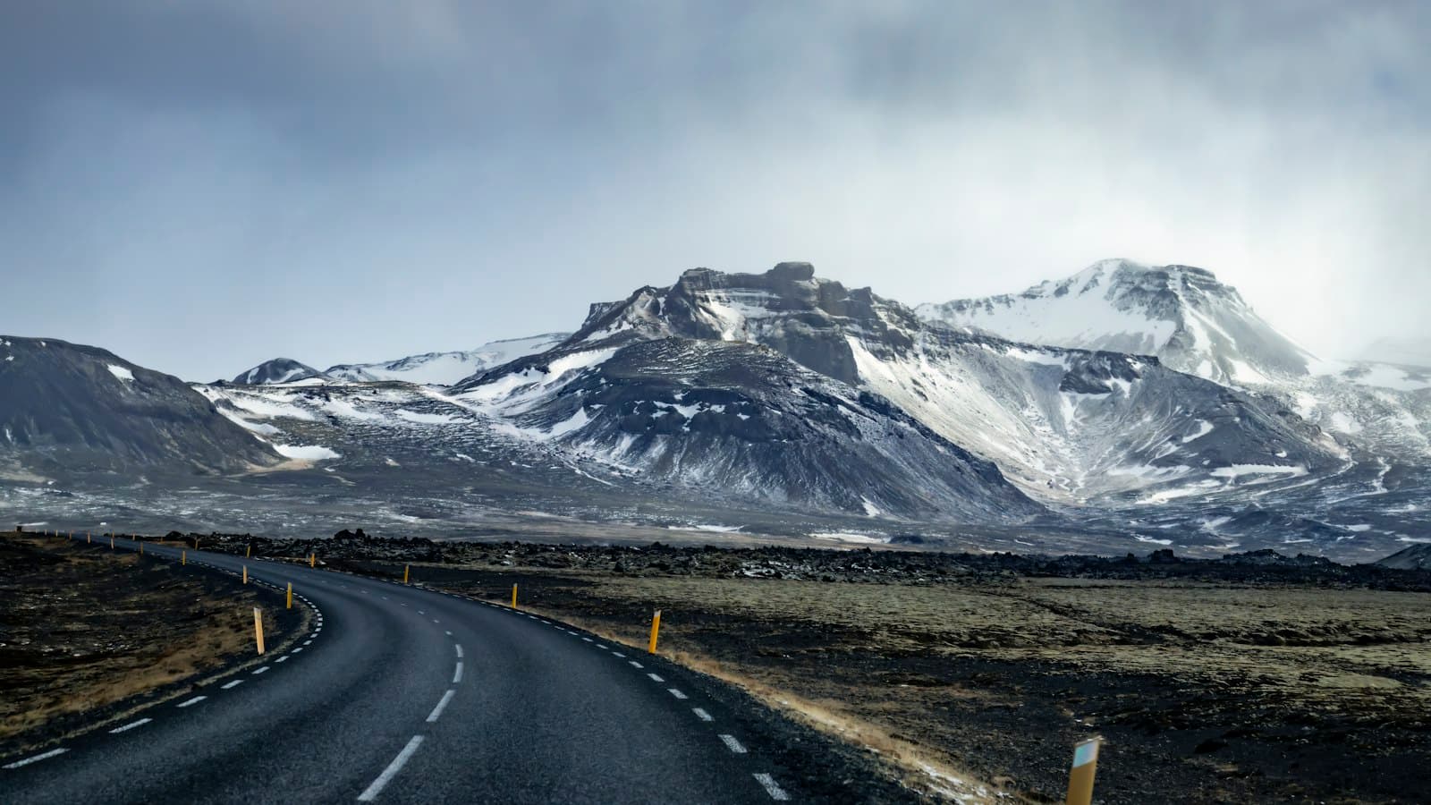 Eine Straße in Richtung schneebedeckter Berge in Island