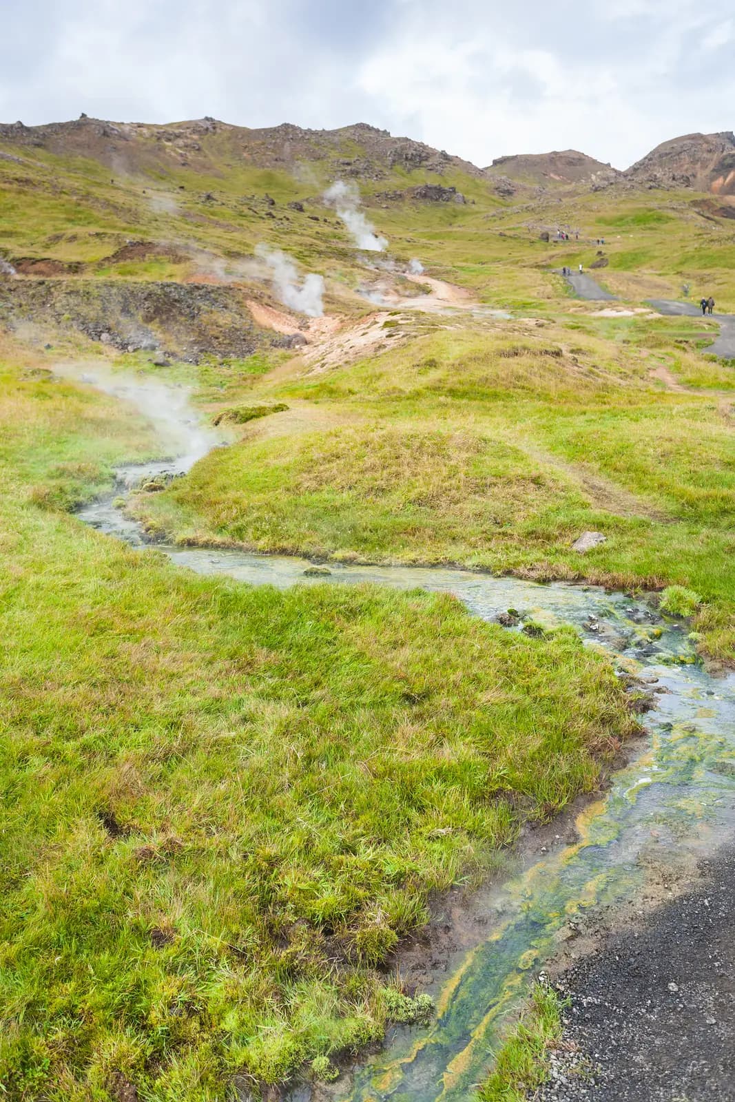 Ein warmer Bach fließt durch grüne Hügel in der Gegend von Hveragerði